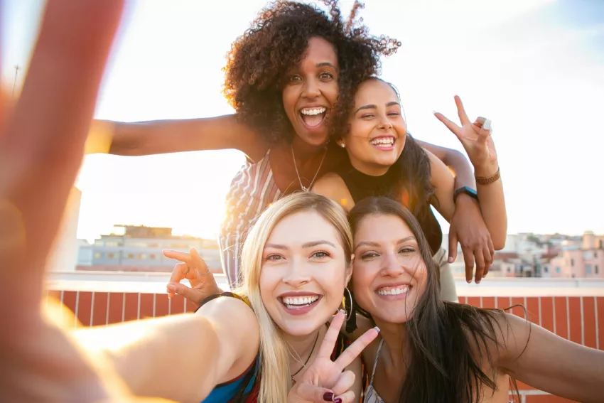 Four confident young women of diverse backgrounds smiling and laughing together on a rooftop